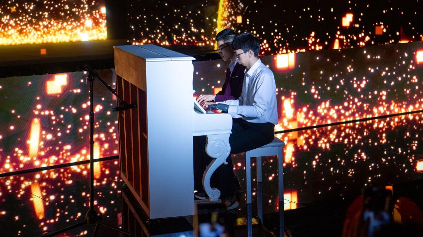 智能仿生手使用者古月與少年鋼琴家舒海峰合奏。主辦方供圖